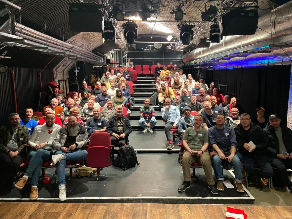 A London theatre social club group gathered in a studio theatre before a performance