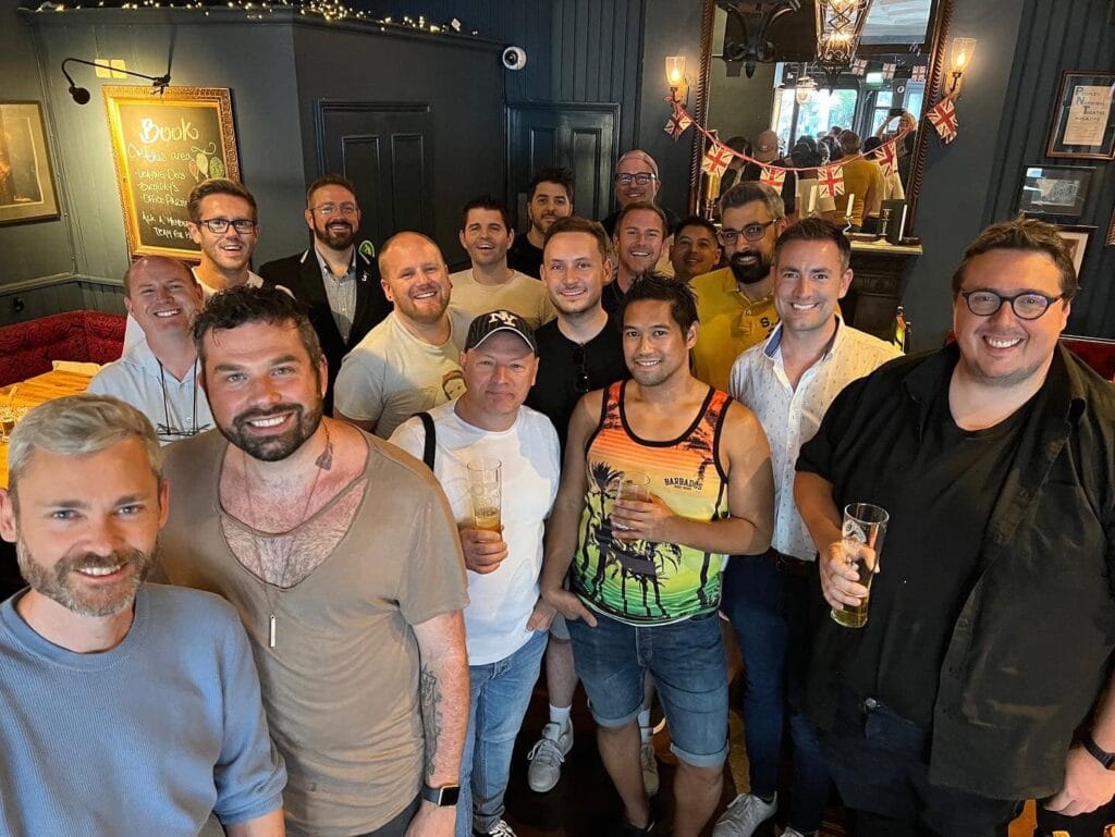 Friends having drinks at a gay theatre night social in a London bar