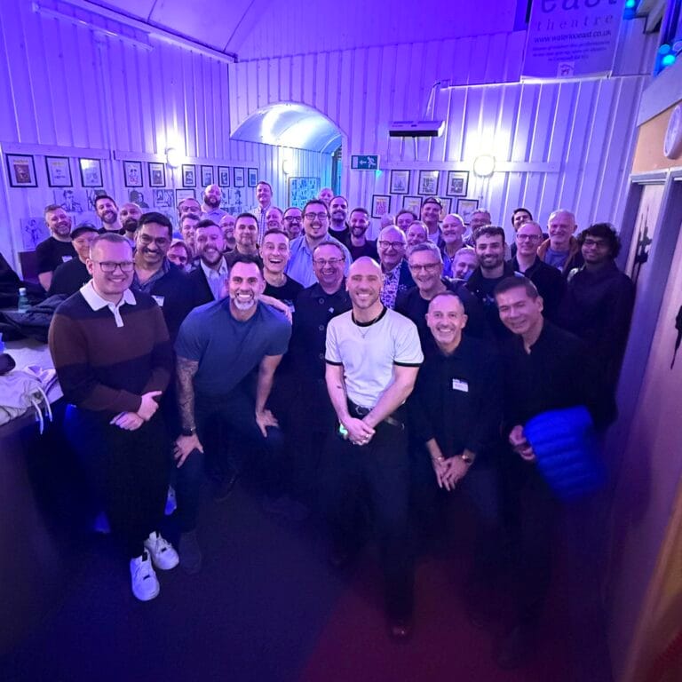 Members at an LGBTQ+ theatre social in a London venue with stage lighting